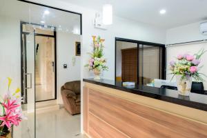 普吉镇The Topaz Residence Phuket Town的大堂设有花瓶装花的前台