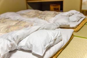 Kita-noda堺のお宿 旧星賀亭的一组坐在床上的白色毯子