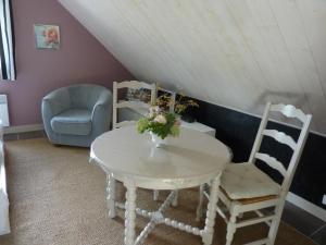 Le Molay-Littry拉库奥卢普住宿加早餐旅馆的一张带两把椅子的白色桌子和一张带鲜花的桌子