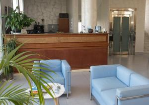 切萨雷奥港Hotel Aurora的大堂设有2把蓝色椅子和1个柜台