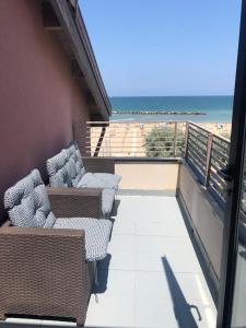 里米尼Hotel Melita Beach Experience的一个带椅子的阳台,享有海滩美景
