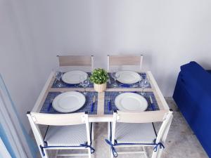 科尼尔-德拉弗龙特拉Conil Centro & Playa, descanso perfecto, Aire Ac y WIFI -SOLO FAMILIAS Y PAREJAS-的一张桌子,上面有两把椅子和盘子,还有一株植物