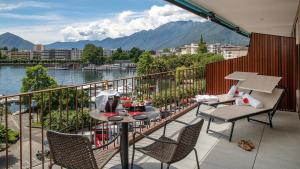 洛迦诺Hotel Lago Maggiore - Welcome!的阳台配有桌椅,享有水景。