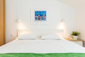 希贝尼克Jadrija Bay的卧室配有一张带绿毯的白色床