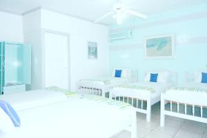 马萨亚伊万尼亚酒店的白色的客房设有三张床和吊扇。