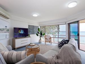 士兵点Pelican Sands 3 stunning waterfront unit with magical water views and air conditioning的带沙发和电视的客厅