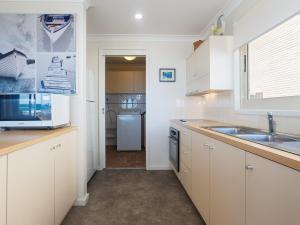 安娜湾The Whale Watcher waterfront unit with stunning views level access的厨房配有白色橱柜、水槽和冰箱。