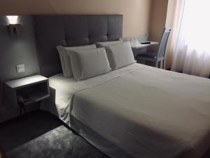 里斯本艾克塞西尔酒店的卧室配有一张白色大床和一把椅子