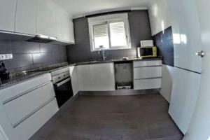 奥利瓦Apartamento de Cristina的一间设有白色橱柜和窗户的大厨房