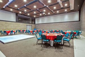 坎昆Wyndham Garden Cancun Downtown的宴会厅配有红色和蓝色的桌椅