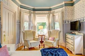 梅戈格La Belle Victorienne的一间卧室配有两把椅子、一台电视和一张床