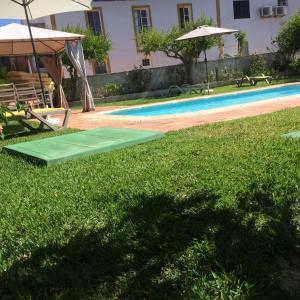 阿尔特Cerro da Janela Hostel的游泳池旁的绿色垫子,带遮阳伞