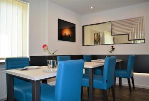 斯图加特Hotel BaWü的一间带桌子和蓝色椅子的用餐室
