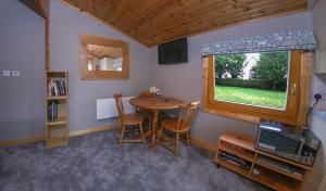 克兰The Cabin @ Willowmere (Garden Log Cabin)的一间带桌椅和窗户的用餐室