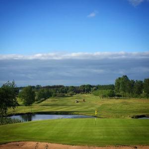巴斯塔德Äppelgårdens Golfklubb的享有带池塘的高尔夫球场的景色