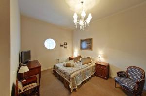 Mālpils马尔皮尔斯庄园酒店的一间卧室配有一张床、一台电视和吊灯。