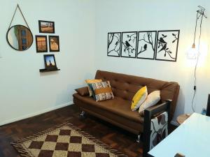 阿雷格里港Amplo, aconchegante e pertinho de tudo的客厅配有棕色的沙发和墙上的照片