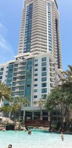 黄金海岸Crown Towers Resort Private Apartments的一座大型建筑,前面的水面上的人