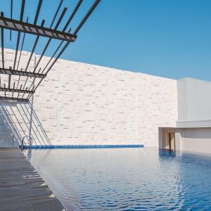 日惹Aveta Hotel Malioboro的白色砖墙前的游泳池