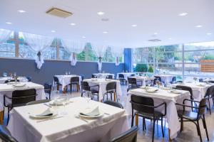 伊斯拉Hotel Los Arces的餐厅设有白色的桌椅和窗户。