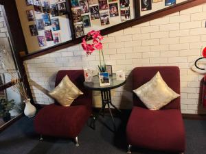 格伦因尼斯安娜贝拉格伦斯尼斯汽车旅馆的两张红色的椅子和一张带花瓶的桌子