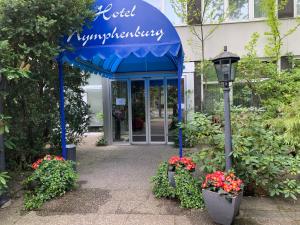 慕尼黑Hotel Nymphenburg City - München的一座建筑,有蓝色遮阳篷,花朵和街道灯