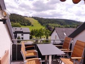 维林根Fewo Blumes Bergfrieden mit MeineCardPlus的阳台配有桌椅和绿色田野。