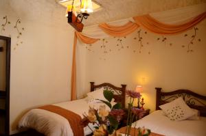 库斯科库斯科乌奈同姆布精品酒店的卧室配有两张床,墙上挂着鲜花。