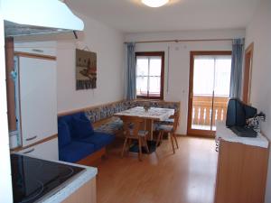 瓦尔道拉Appartement Gandler的厨房以及带桌子和蓝色沙发的客厅。