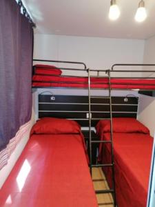 阿尔本加Camping Delfino的一间卧室配有两张双层床,铺有红色床单