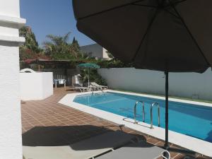 维拉Villa PaloMayor的一座房子旁带遮阳伞的游泳池