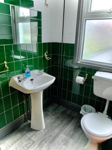 曼彻斯特Manchester Stay Hotel的绿色瓷砖浴室设有水槽和卫生间