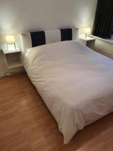 鹿特丹Single family home in Hillegersberg - Schiebroek的一张白色的大床,两张桌子上有两个灯