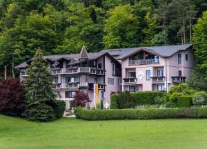 沃尔特湖畔佩莎赫Hotel Garni ELISABETH的一座大粉红色的建筑,有树木背景