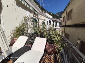 阿马尔菲Residenza Del Duca Rooms & Apartments的大楼内的阳台配有白色椅子和植物
