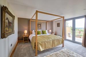 哈罗盖特Harrogate Barns的一间卧室设有一张带大窗户的天蓬床