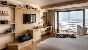 北芭堤雅Pullman Pattaya Hotel G的酒店客房配有一张床、一张书桌和一台电视。