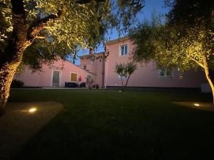 法扎纳Apartments Prodan的粉红色的房子,晚上有绿色的院子