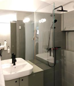 林茨Gemütliche Wohnung im Herzen von Linz的一间带水槽和玻璃淋浴的浴室