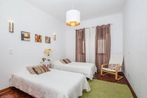 西尔韦斯Casa Jacarandá的白色客房 - 带两张床和椅子