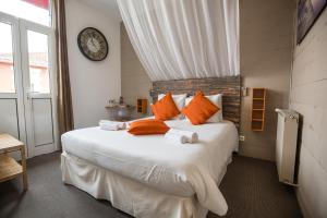阿卡雄Hôtel Familial L'Ostréi的一间卧室配有一张带橙色枕头和时钟的大床