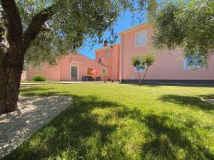 法扎纳Apartments Prodan的院子里有树的粉红色房子