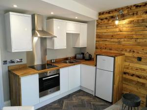 布里斯托Derby Den by Cliftonvalley Apartments的厨房配有白色橱柜和木墙