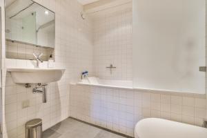 阿姆斯特丹阿姆斯特丹运河酒店的白色瓷砖浴室设有水槽和卫生间
