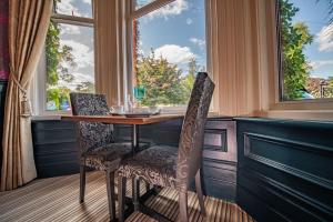 伯恩茅斯Amarillo Guesthouse的窗户间里的一张桌子和两把椅子