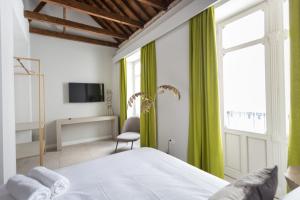 马拉加W Thyssen house的一间卧室配有一张带绿色窗帘的床和电视。