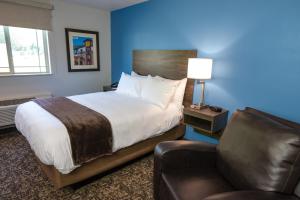 亨特斯维尔My Place Hotel-Huntersville, NC的一间卧室配有一张床、一把椅子和一张沙发