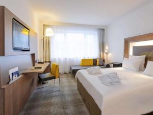 汉诺威汉诺威诺富特酒店的酒店客房设有一张大床和一张书桌。
