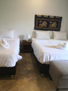 华欣Tropical House​的一间卧室配有两张带白色床单和桌子的床