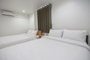 曼谷INTERest POSHTEL的配有白色床单的客房内的两张床